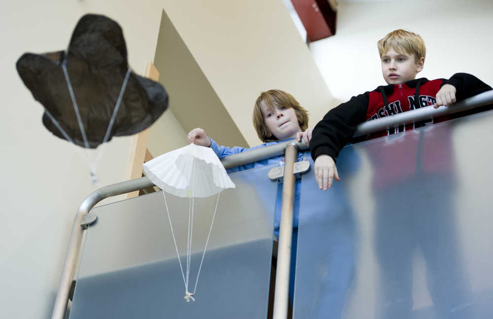 Auke Bay Elementary School fifth-graders Alex Filkov, right, and Kean Buss take turns releasing their parachutes during an class engineering project on Friday. The students learned the effects of canopy size, materials and suspension line length in making the best parachutes.