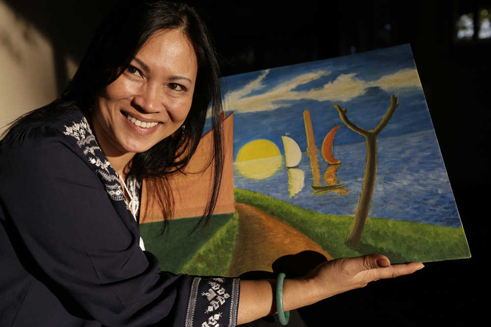 Erika Colligan poses with a painting made by her father Tuesday, Jan. 12, 2016, in San Diego. After three decades searching for her father's artwork - paintings the South Vietnam pilot made for the U.S. Air Force aviators who trained him during the Vietnam war, Colligan recently found one. The painting gave her the first tangible sliver of the father she never got the chance to know. (AP Photo/Gregory Bull)