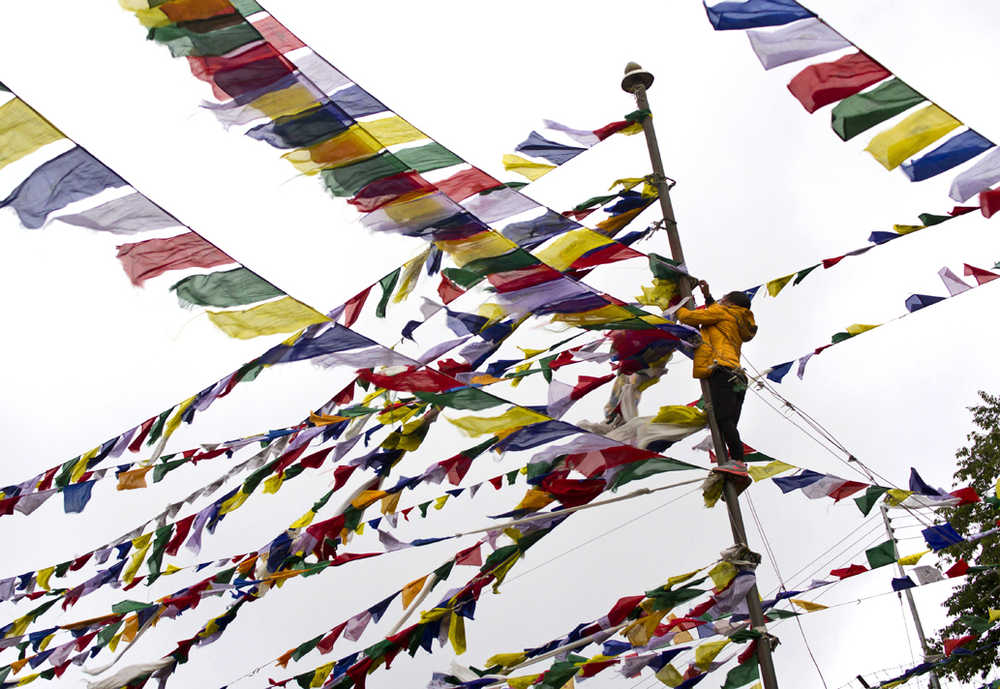 An exile Tibetan ties multi-color prayer flags called wind horse or lungta on a tall pole on the third day of the Tibetan New Year in Dharmsala, India, on Thursday.