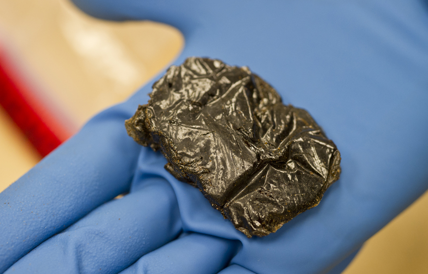 A Juneau Police Department officer holds a package of black tar heroin at the JPD station in December 2015.