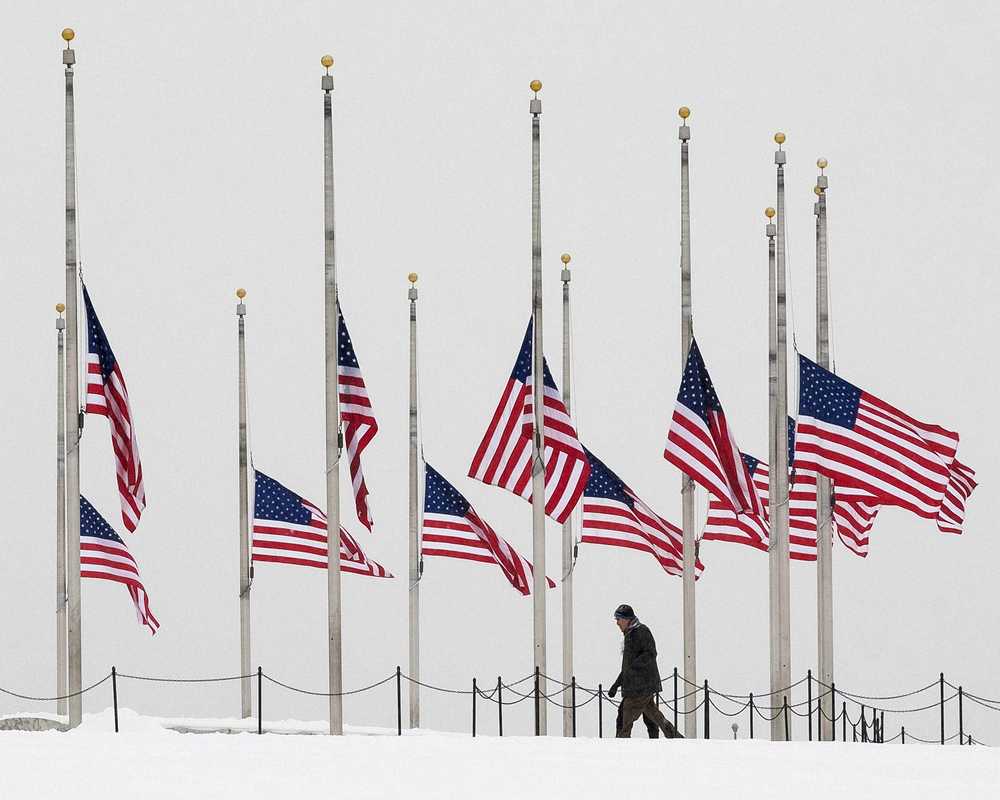 A vistor to the Washington Monument walks past flags flying a half-staff in honor of Supreme Court Justice Antonin Scalia on a wintry President's Day on Monday in Washington.