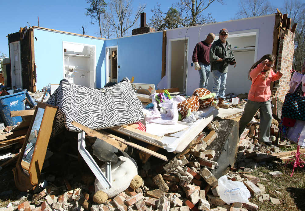 Residents and neighbors salvage items from the debris of a home that was damaged by severe weather that struck the prior evening, on Jefferson Avenue in Century, Fla., Tuesday, Feb. 16, 2016. (AP Photo/Michael Snyder)