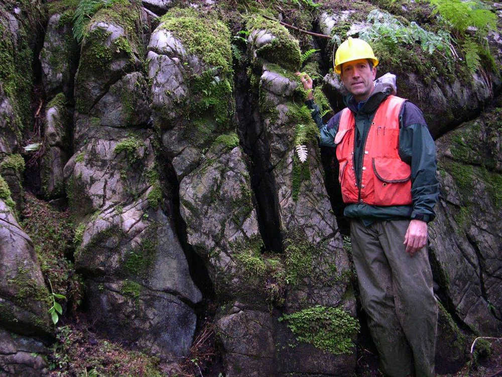 Dave D'Amore stands with exposed limestone rock, which shows signs of weathering, or erosion. Weathering rock consumes atmospheric carbon dioxide and stores the byproducts of the weathering reaction as organic carbon in the soil.