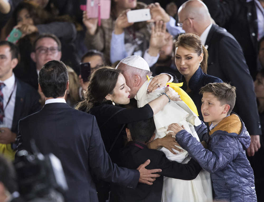 Flanked by Mexico's President Enrique Pena Nieto and first lady Angelica Rivera, Pope Francis is embraced by children on his way to a staging area, for a farewell ceremony, before his departure, at the Abraham Gonzalez International Airport in Ciudad Juarez, Mexico, Wednesday, Feb. 17, 2016. Francis returned to Italy after a five-day visit in Mexico. His plane took off from the border city of Ciudad Juarez after night fell Wednesday. (AP Photo/Ivan Pierre Aguirre)