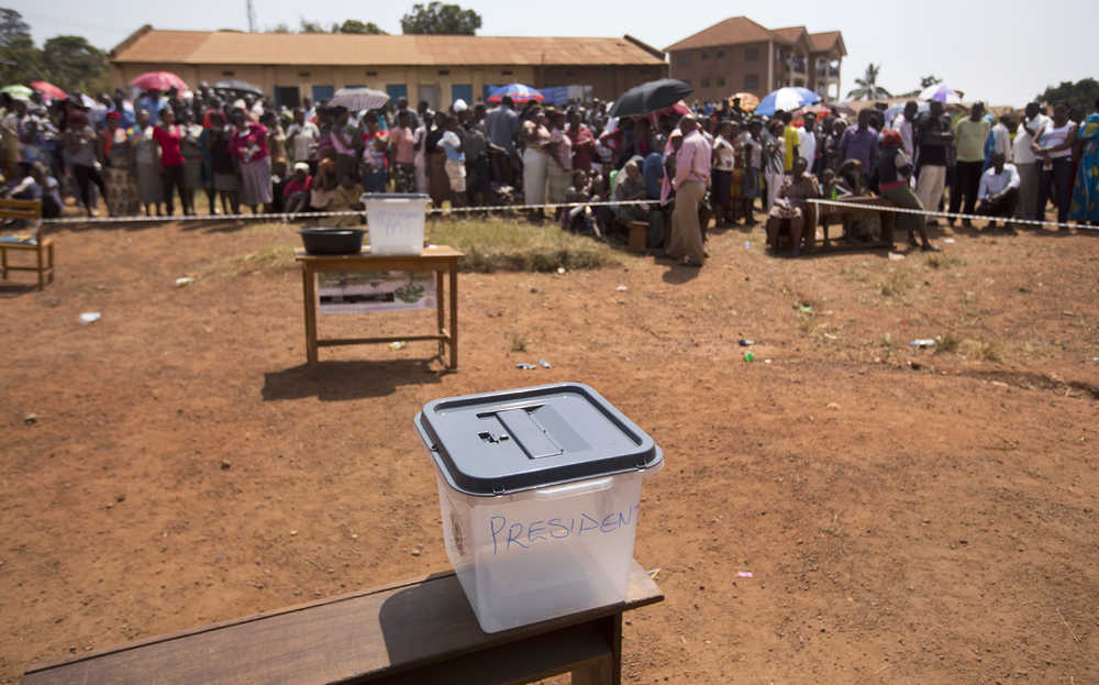 Voters queue at a polling station where a ballot box sits empty Thursday in the capital Kampala, Uganda. Five hours after voting was due to start no voting papers had yet arrived.
