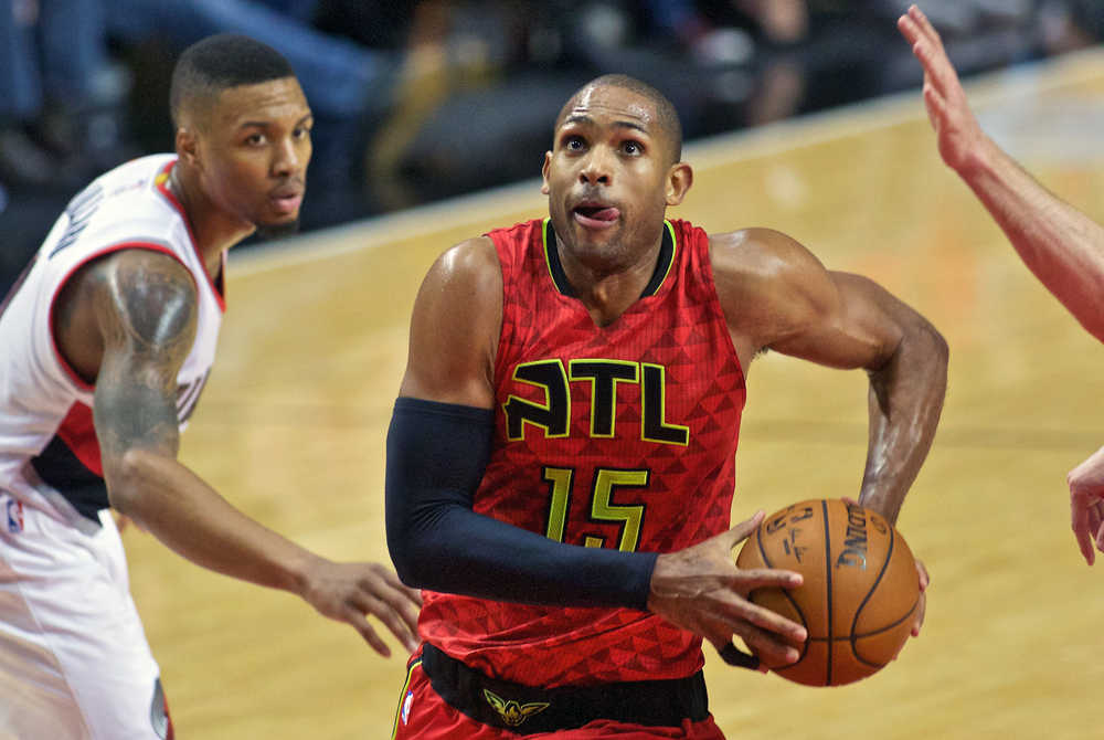 In this Jan. 20 photo, Atlanta Hawks center Al Horford drives past Portland Trail Blazers guard Damian Lillard during the second half.  The Hawks All-Star said Wednesday he expects to remain in Atlanta, and he is the ideal fit for coach Mike Budenholzer's system. But he will be a free agent this summer, and the Hawks could look to move him if they think they would lose him for nothing in a few months.
