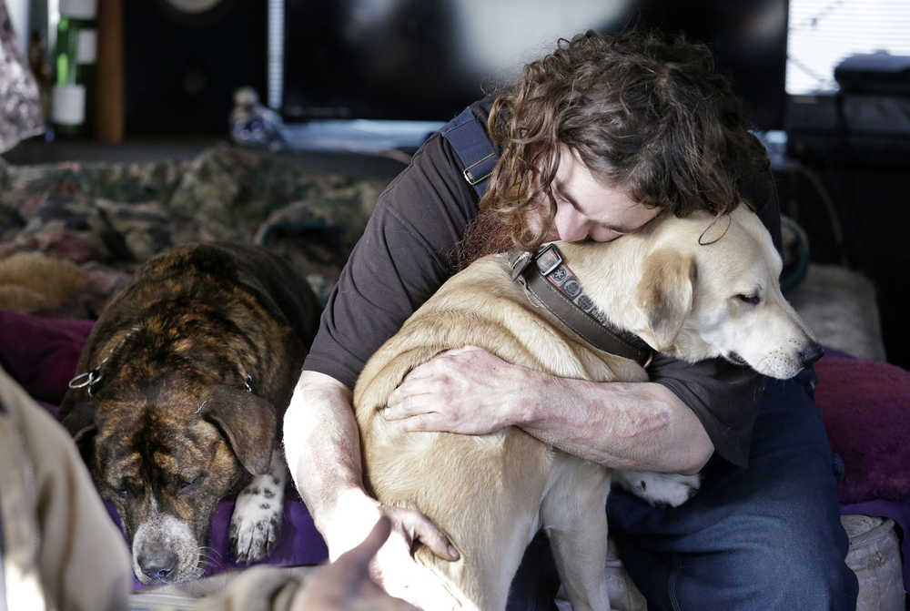 Joshua Madrid hugs his dog, Cheese, as Loki lies next to them in Madrid's bus, parked in a temporary city-approved area for people living in their vehicles in Seattle on Tuesday, Feb. 9, 2016. Seattle has the third-highest number of homeless people in the U.S. (AP Photo/Elaine Thompson)