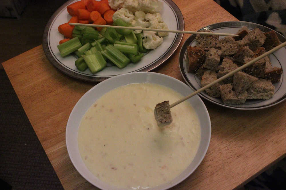 Cheese fondue with bread and vegetables.