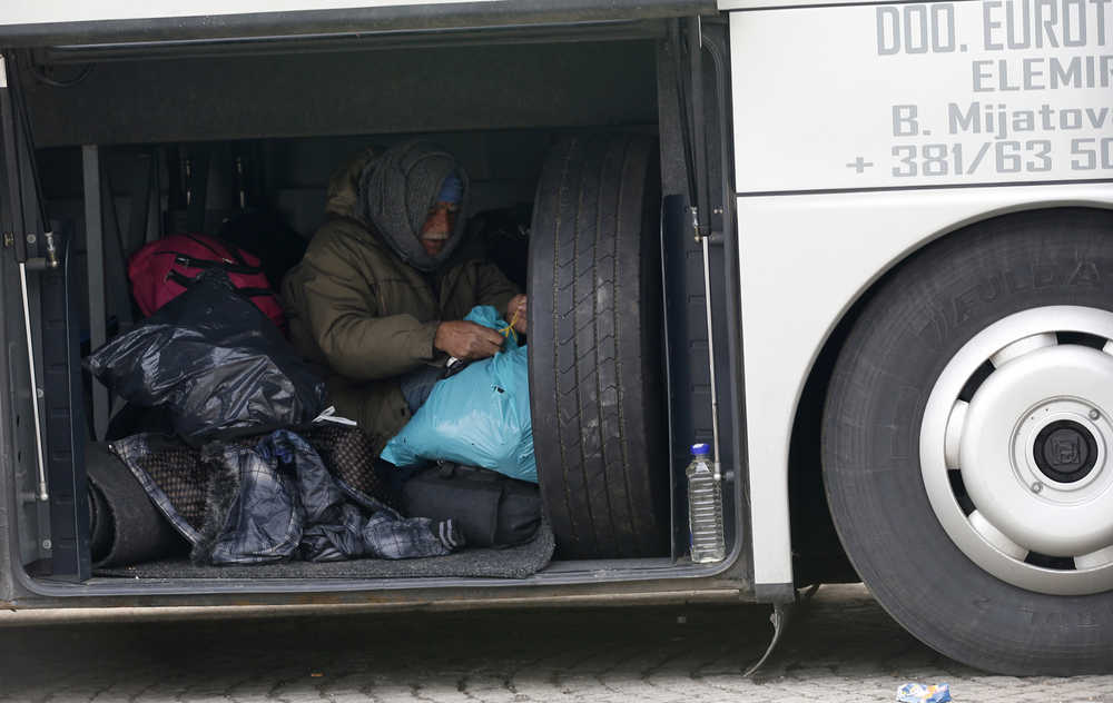 A migrant rests in a bus trunk Wednesday as he waits to leave for Croatia from the village of Adasevci, Serbia.