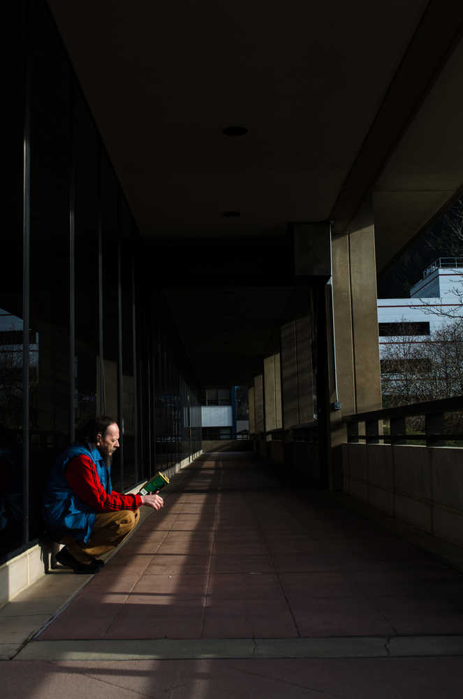 A Juneau resident reads while enjoying Tuesday's afternoon sunshine at the State Office Building.