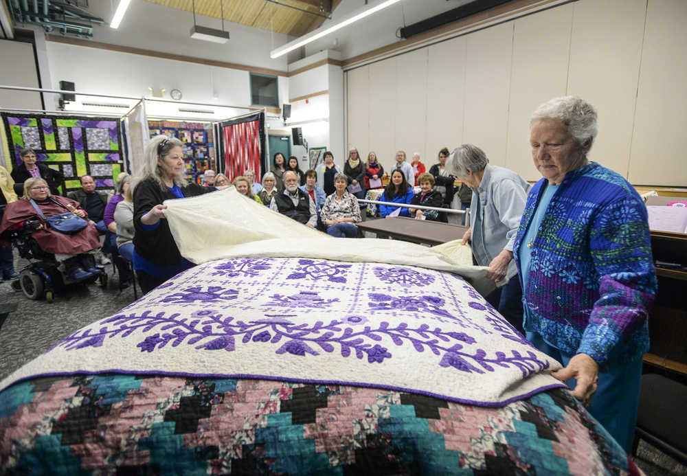 In this Feb. 13 photo, Mary Castle, far right, straightens a quilt while Valerie Sandusky, left, and Kathy Tillotson fold another quilt during a bed turning at the "Quilting in the Rain" show at the Ted Ferry Civic Center in Ketchikan.