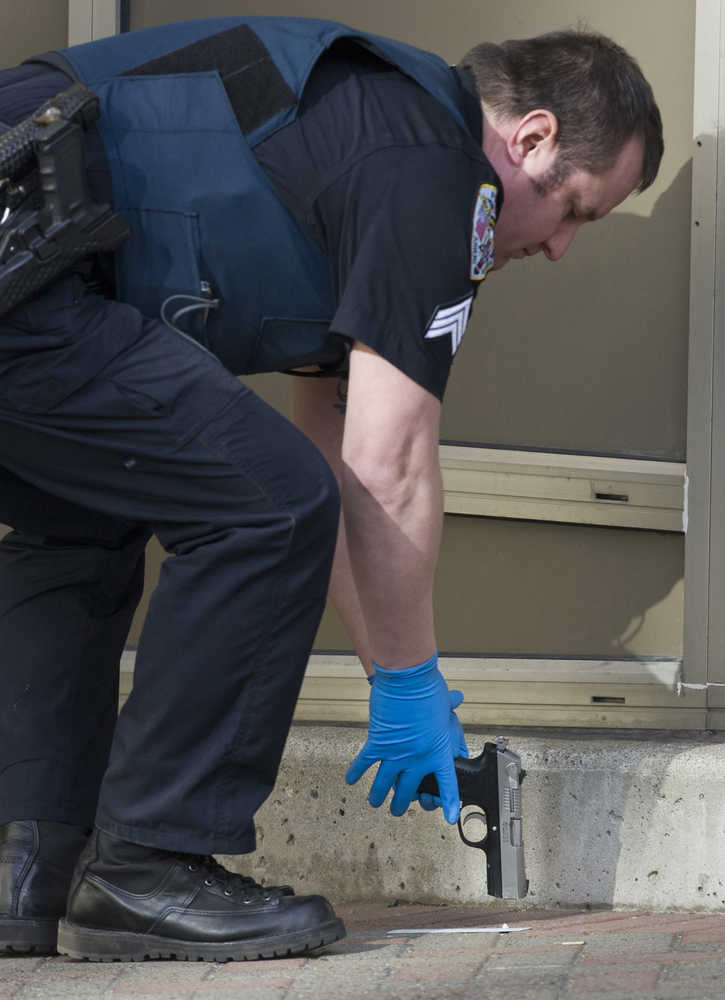 Juneau Police Department Sgt. Chris Gifford collects a handgun found at the scene where a woman reportedly shot herself in front of the main entrance of the Dimond Courthouse on Monday.
