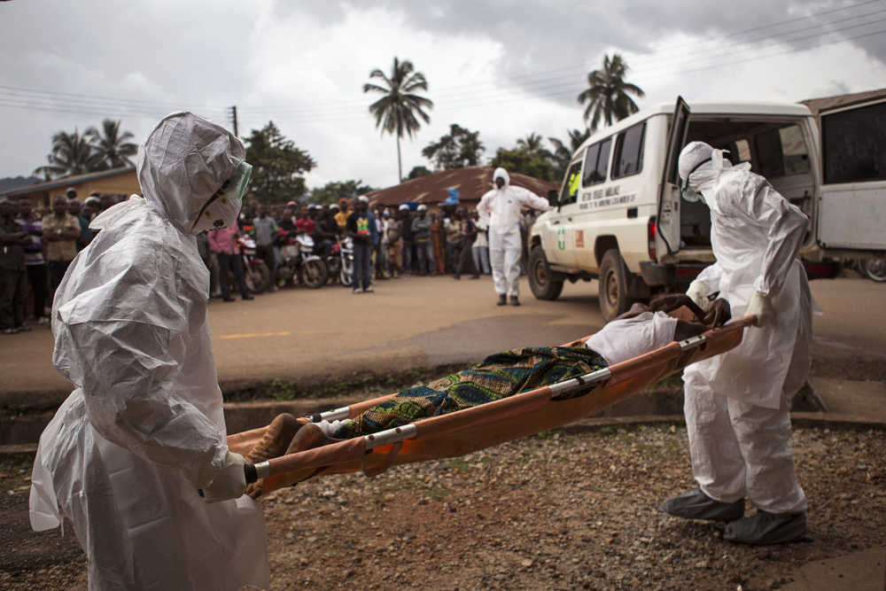 FILE - In this Sept. 24, 2014, file photo, healthcare workers load a man suspected of suffering from the Ebola virus onto an ambulance in Kenema, Sierra Leone. An Associated Press investigation found that Metabiota Inc., an American company given crucial disease-fighting responsibilities in the Ebola outbreak, was criticized for committing one blunder after another - misdiagnosing patients with the virus, feuding with other responders and offering rosy predictions about the course of the epidemic that proved wrong. (AP Photo/Tanya Bindra, File)
