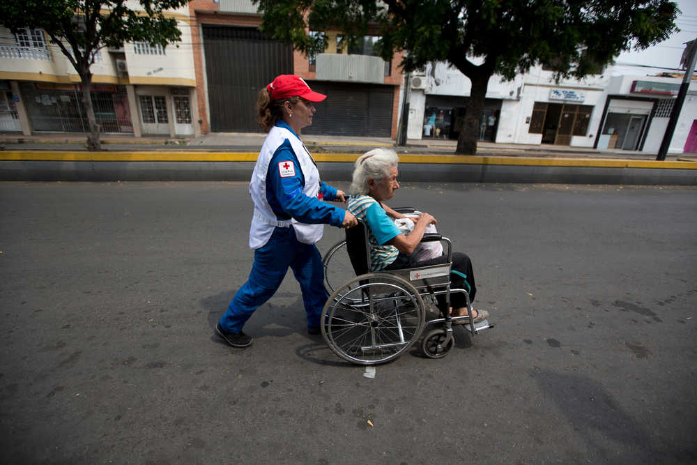 In this March 1 photo, a member of the Colombian Red Cross helps a Colombian patient returning to Venezuela in the border town of San Antonio, Venezuela, after her medical treatment in Cucuta, Colombia.