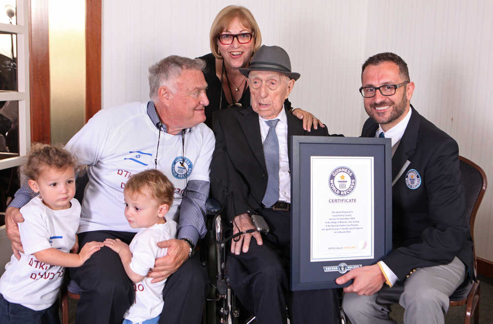 In this undated photo, Marco Frigatti, Head of Records for Guinness World Records, right, poses with Israel Kristal, second right, as he presents a certificate for being the oldest living man in Haifa, Israel.  Kristal is seen with some of his family members, from left to right, grandchildren Nevo and Omer, son Heim Kristal, and daughter Shula Kuperstoch.