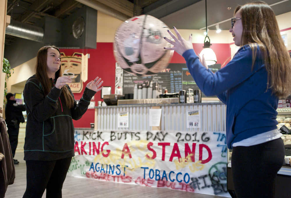 Freshmen Abby Locks, left, and Maya Garza play with a tobacco trivia game ball while manning an anti-tobacco information stand at the downtown Heritage Coffee shop on Wednesday. The students hung anti-tobacco graffiti on clothes lines in the cafe. The national Kick Butts Day is sponsored by the Campaign for Tobacco-Free Kids.