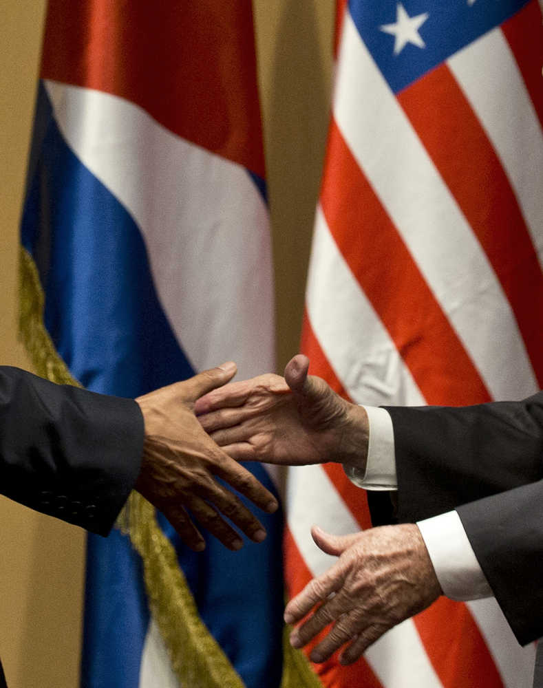 Back dropped by the US and Cuban flags, US President Barack Obama, left, and Cuba's President Raul Castro shake hands after making a joint statement Monday in Havana, Cuba.
