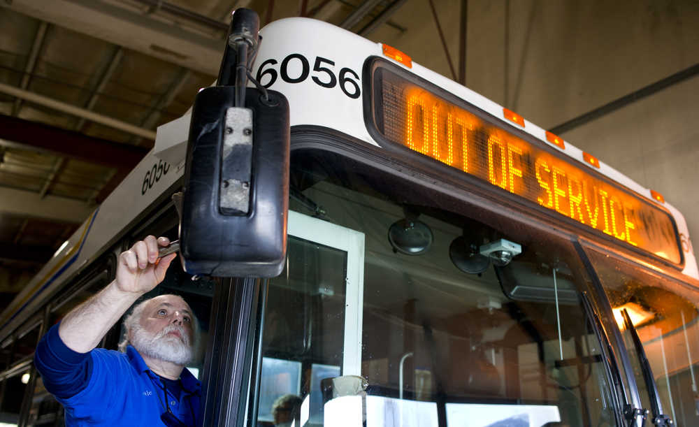 Driver Dale Mazzei cleans mirrors on a bus before starting his route from the city's Capitol Transit bus barn on Thursday.