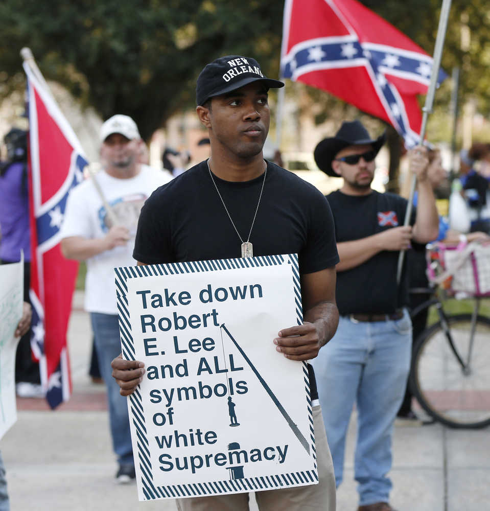 In this Dec. 10, 2015 photo, an unidentified participant holds a sign during a rally lead by the Take 'em Down Coalition, as confederate heritage supporters bear confederate flags nearby in front of City Hall in New Orleans.