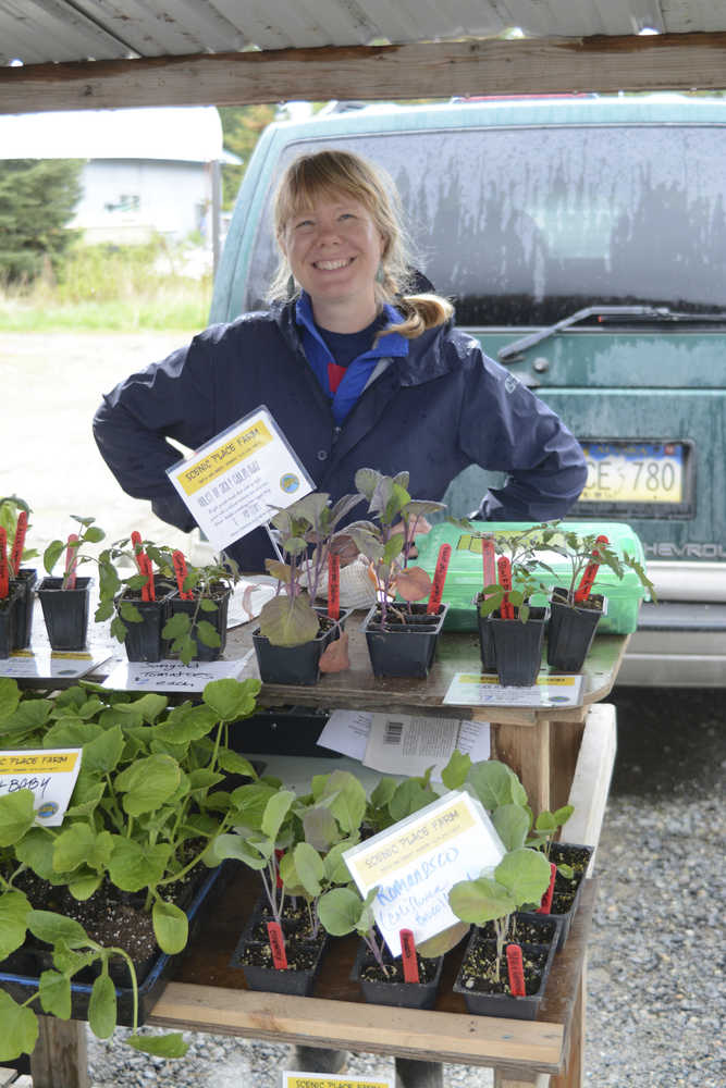 In this May 25, 2015 photo, Jillian Glasgow watches Beth Van Sandt's Scenic Place Peonies and Farm booth at the opening day of the Homer Farmers Market in Homer, Alaska. Glasgow, of Portland, Oregon, is a "woofer," or worker with the Worldwide Opportunities on Organic Farms, program.