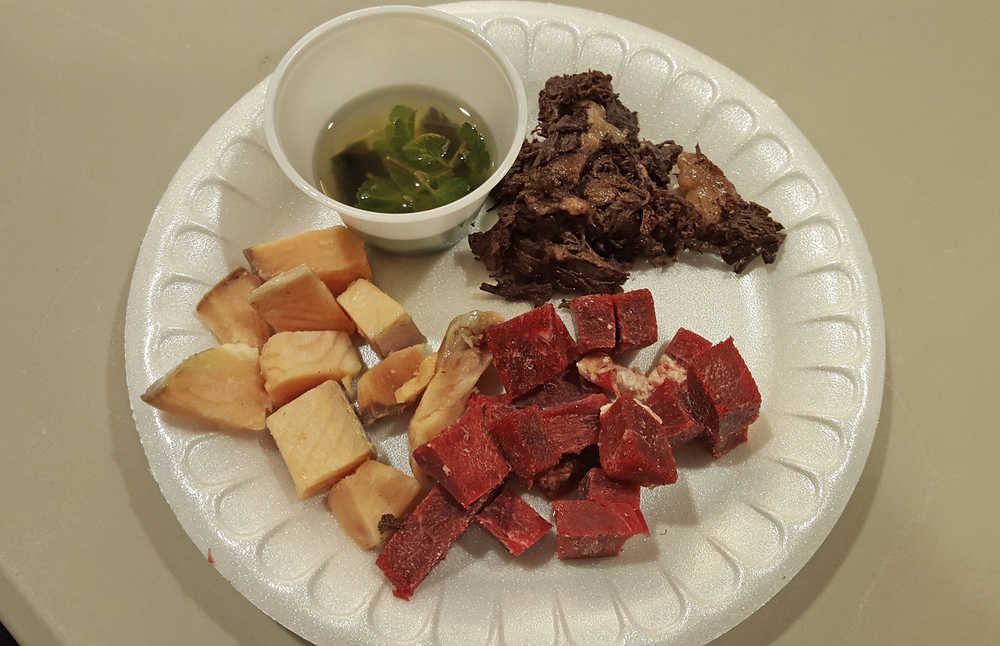In this Feb. 1, 2016 photo provided by Val Kreil, seal oil is served with raw sheefish and caribou and cooked seal meat during a potluck at a nursing home in Kotzebue, Alaska. The Alaska Native organization that operates the home is hoping to regularly serve its nursing home residents the nutrient-rich oil, a traditional staple that's banned in public settings because of its high risk for botulism if not properly processed. (Val Kreil via AP) MANDATORY CREDIT