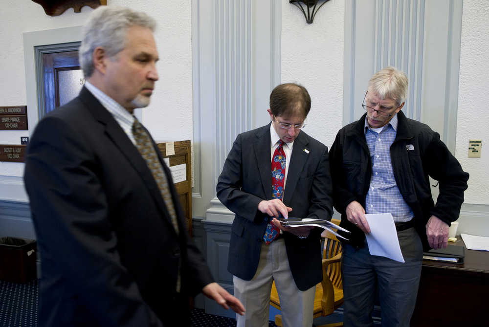 Sen. Pete Kelly, R-Fairbanks, left, walks out of the Senate Finance Committee room as Jesse Kiehl, legislative staff and Juneau's deputy mayor, center, and Bob Bartholomew, Juneau's finance director, look over cuts the city may now face as a result of four bills Kelly introduced Tuesday at the Capitol.