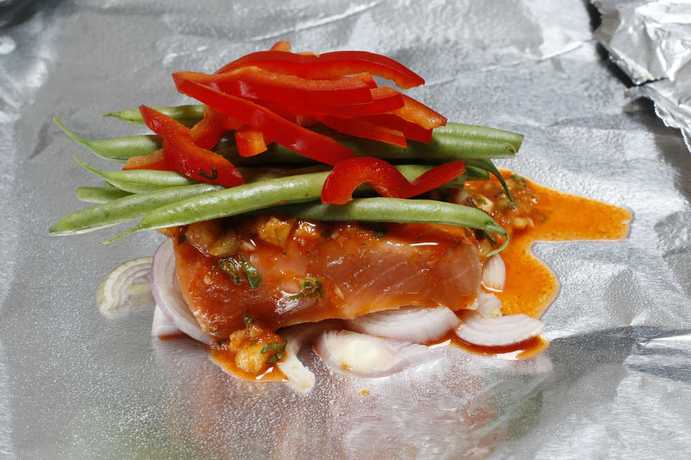 This March 14, 2016, photo shows salmon packets with curry and green beans in Concord, N.H. Baking fish in a foil packet keeps it moist and makes it difficult to overcook. It also is a great way to simultaneously cook sides, such as the green beans in this recipe.