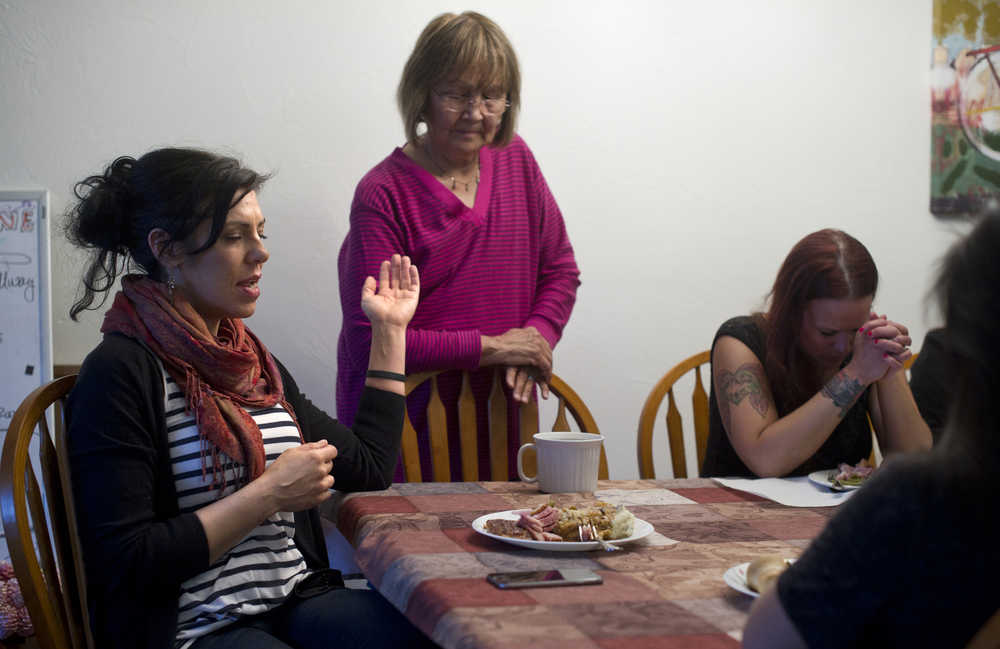 Haven House Director Kara Nelson, left, leads a prayer at a group dinner on Tuesday. Also shown are Board Chair June Degnan, center, and resident Andrea Robinson. Haven House is celebrating its one-year anniversary as a transitional home for recently released female prisoners and women coming out of substance abuse or mental health treatment.