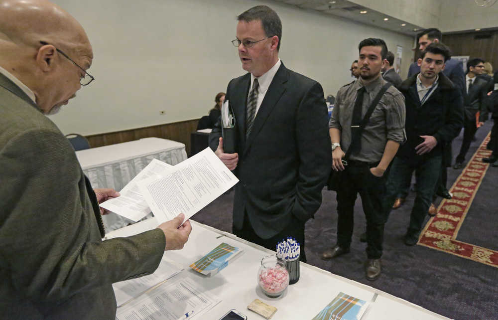 FILE - In this April 22, 2015 file photo, Ralph Logan, general manager of Microtrain, left, speaks with James Smith who is seeking employment during a National Career Fairs job fair in Chicago. U.S. employers notched another solid month of hiring in March by adding 215,000 jobs, driven by large gains in the construction, retail and health care industries. Despite the jump, the Labor Department said Friday, April 1, 2016 that the unemployment rate ticked up to 5 percent from 4.9 percent. (AP Photo/M. Spencer Green, File)
