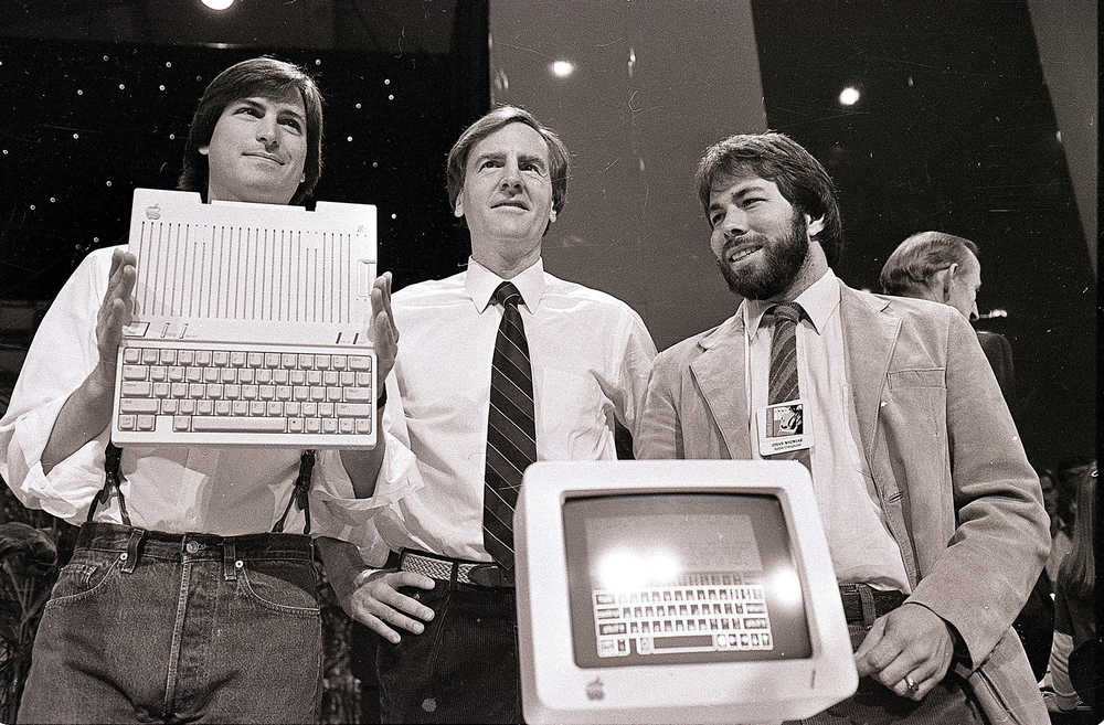 FILE - In this April 24, 1984, file photo, Steve Jobs, left, chairman of Apple Computers, John Sculley, center, president and CEO, and Steve Wozniak, co-founder of Apple, unveil the new Apple IIc computer in San Francisco. Apple has turned 40, and it's a very different company from the audacious startup that Jobs and Wozniak launched in a Silicon Valley garage in 1976. (AP Photo/Sal Veder, File)