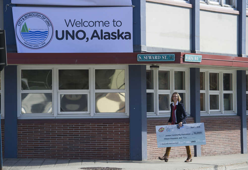 IMAGE DISTRIBUTED FOR MATTEL, UNO - Amy Skilbred, Executive Director of the Juneau Community Foundation, walks away from Juneau, Alaska's City Hall with a $15,000 check presented to her by Mattel on Friday, April 1, 2016. As part of an April Fools' promotion, the city of Juneau and Mattel announced a renaming of Juneau to UNO. (Michael Penn/AP Images for Mattel, UNO)