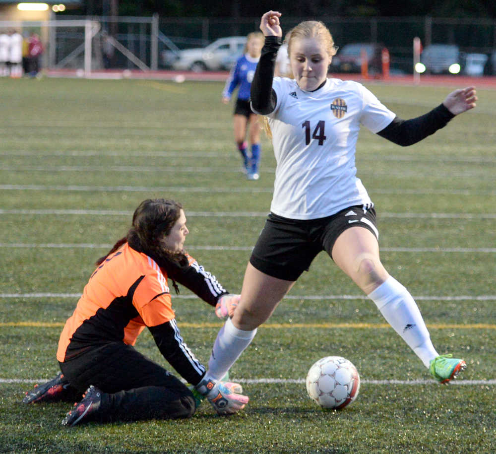 Ketchikan High School junior Angel Spurgeon (14) tries to kick the ball past Thunder Mountain senior goaltender Tianna Huber (1) on Friday, April 1, 2016, during the Lady Kings' 2-0 win against the Lady Falcons at Esther Shea Field.