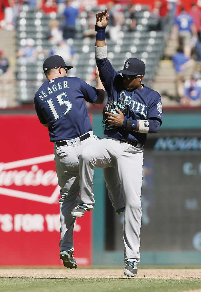 Seattle Mariners Kyle Seager (15) and Robinson Cano, right, celebrate a 9-5 win over the Texas Rangers after a baseball game, Wednesday, April 6, 2016, in Arlington, Texas. (AP Photo/Brandon Wade)