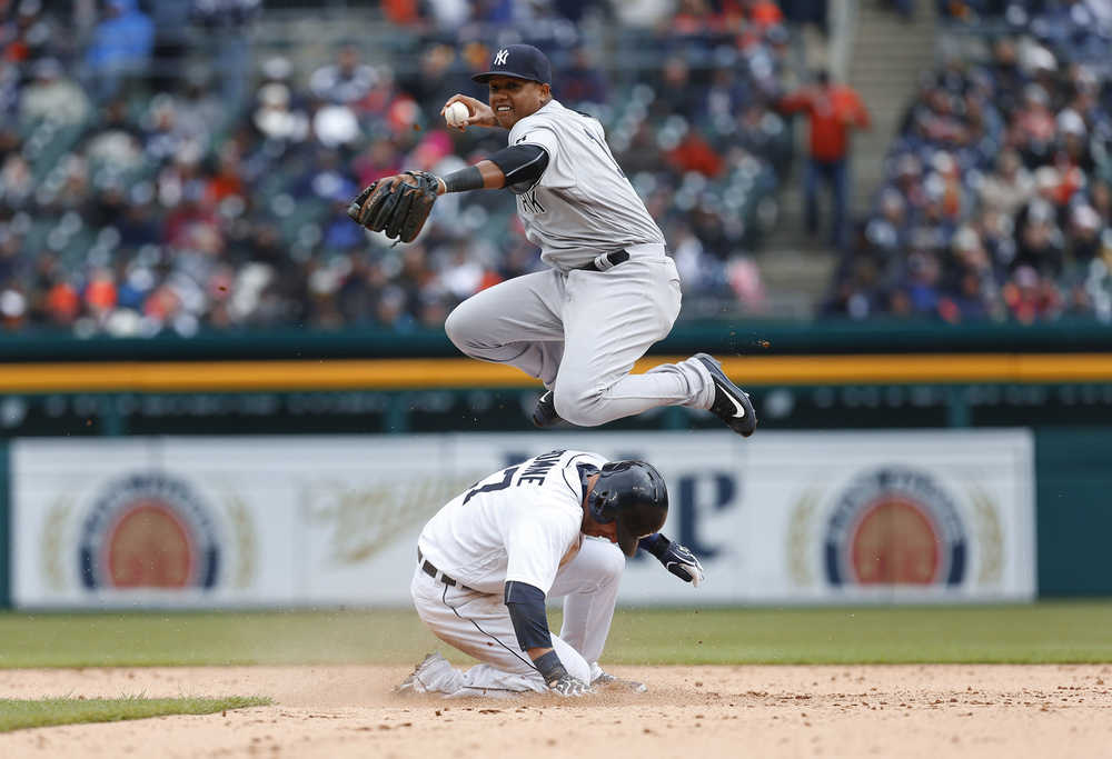 Detroit Tigers' Andrew Romine slides safely into second base as New York Yankees second baseman Starlin Castro throws to first base on a James MCann ground ball in the eighth inning Friday in Detroit. Romine was originally called out on the play but was overturned on video replay.
