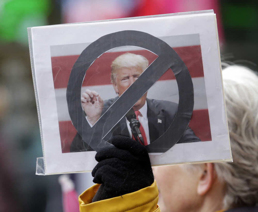 A woman holds a sign near the Times Union Center before a rally for Republican presidential candidate Donald Trump in Albany, N.Y., Monday, April 11, 2016. (AP Photo/Mike Groll)