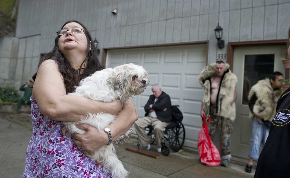 Hazel LeCount holds her pet dog, Serenity, as she waits with other residents to be let back into the Channel View Apartments on Sunday after a fire broke out in a unit on the fifth floor.