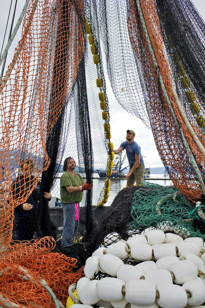 Haley Kelley, left, Bill White, center, and Cosmo Fudge check their 250-fathom long seine net for holes while docked at the Statter Memorial Boat Harbor in Auke Bay in July 2012. Juneau's Docks and Harbors Board is working to revise a portion of city code pertaining to a commercial fishing moorage discount.