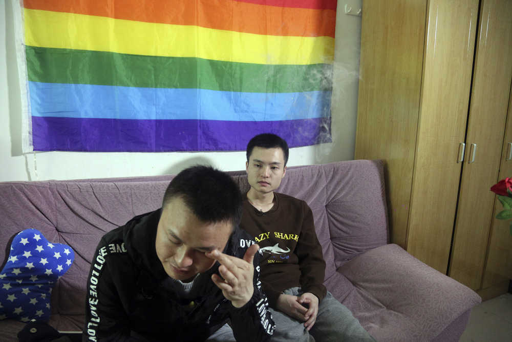 In this photo taken Tuesday, April 12, 2016,  Sun Wenlin, right,  sits with his partner Hu Mingliang at home a day before going to court to argue in China's first gay marriage case in Changsha in central China's Hunan province.  A judge on Wednesday, April 13, 2016 ruled against the gay couple in China's first same-sex marriage case that attracted several hundred cheering supporters to the courthouse and was seen as a landmark moment for the country's emerging LGBT rights movement. (AP Photo/Gerry Shih)