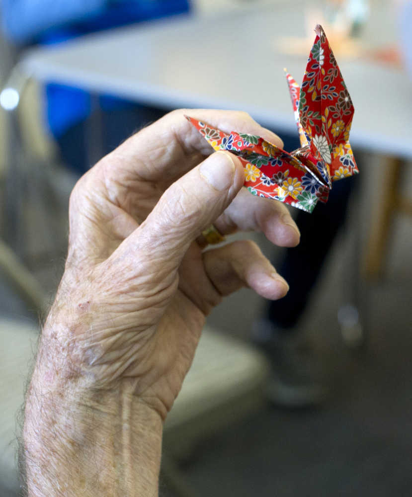 A Juneau Pioneer Home resident holds a paper crane made during a visit by Haborview Elementary School students on Thursday.