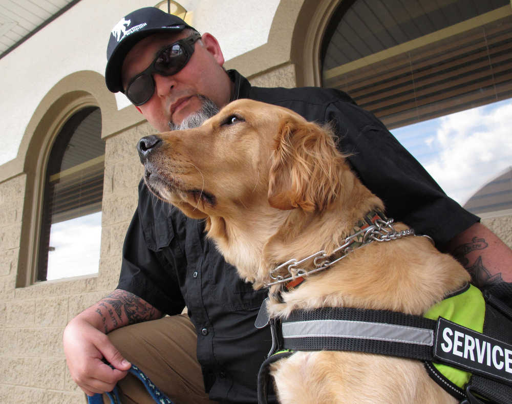 In this Thursday, March 24, 2016 photo, Army veteran Joe Aguirre drapes a tattooed arm across the back of his service dog, Munger, in Fayetteville, N.C. The Department of Veterans Affairs is in the middle of a multi-year study to determine whether it should pay for such psychiatric service dogs. (AP Photo/Allen G. Breed)