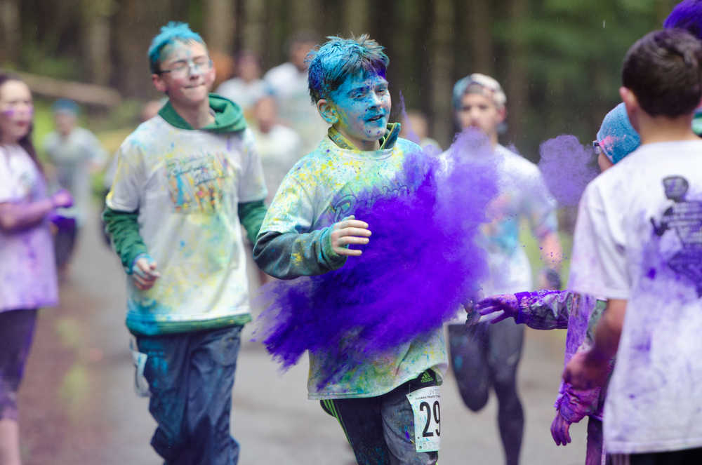 A runner makes his way through the purple station toward the finish line during Sunday's Runners celebrate their success by throwing many different colors up in the air during Sunday's Raining Colors 5K Fun Run. Proceeds benefit the Juneau Youth Triathlon Club..