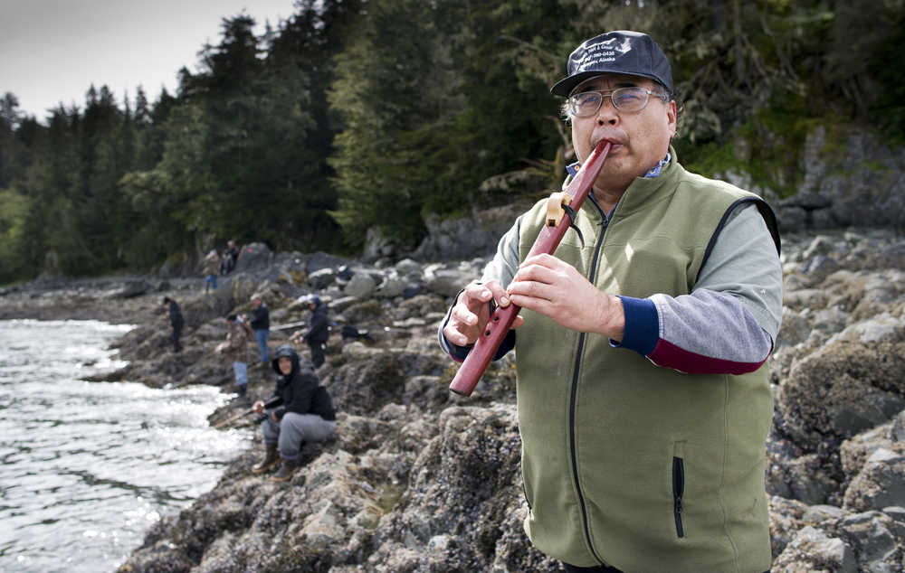 Rudy Isturis takes a break to play his Native American flute while fishing for king salmon off the rocks at False Outer Point on Monday. Fishing was slow but fishermen caught a few fish during the weekend. When asked why he plays the flute, Isturis responded, "I play for myself, I play for those that are gone, I pray for those, I play for those that don't know they are gone, and simply, I play for everyone."