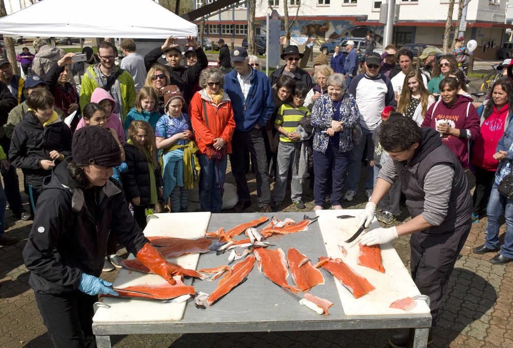 Nicole Flake, left, of Taku Smokeries, competes against Saul De La Mora, of Alaska Glacier Seafoods, in the professional fish filleting contest during the 2015 Juneau Maritime Festival at Marine Park in May 2015. Three people from each seafood processer competed to fillet two coho salmon and were judged for time and accuracy.