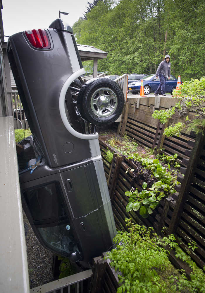 The driver, who did not wish to be identified, walks by his upended truck at the Westridge Condominiums on Hermit Street in downtown Juneau on Friday. The driver was unhurt in the accident that happened about noon on Friday. The driver, with a construction company working at the condominiums, said his brakes failed to work.