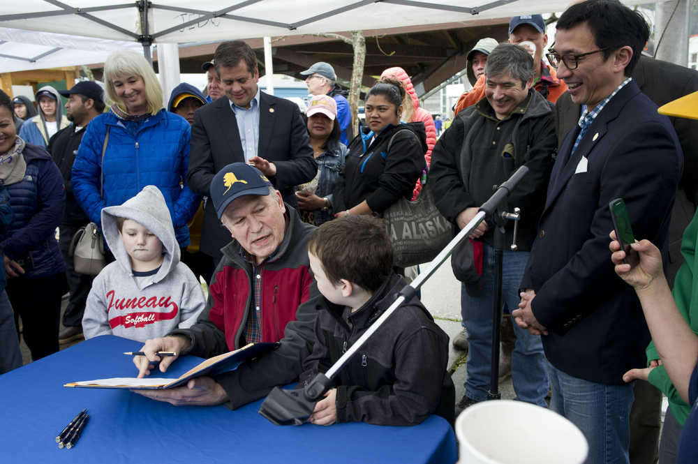 Gov. Bill Walker signs a bill creating an Alaska Salmon Day with the help of Maverick Sprague, 5, left, and his brother, Oden, 6, during the Juneau Maritime Festival at Marine Park in Juneau on Saturday, May 7, 2016.