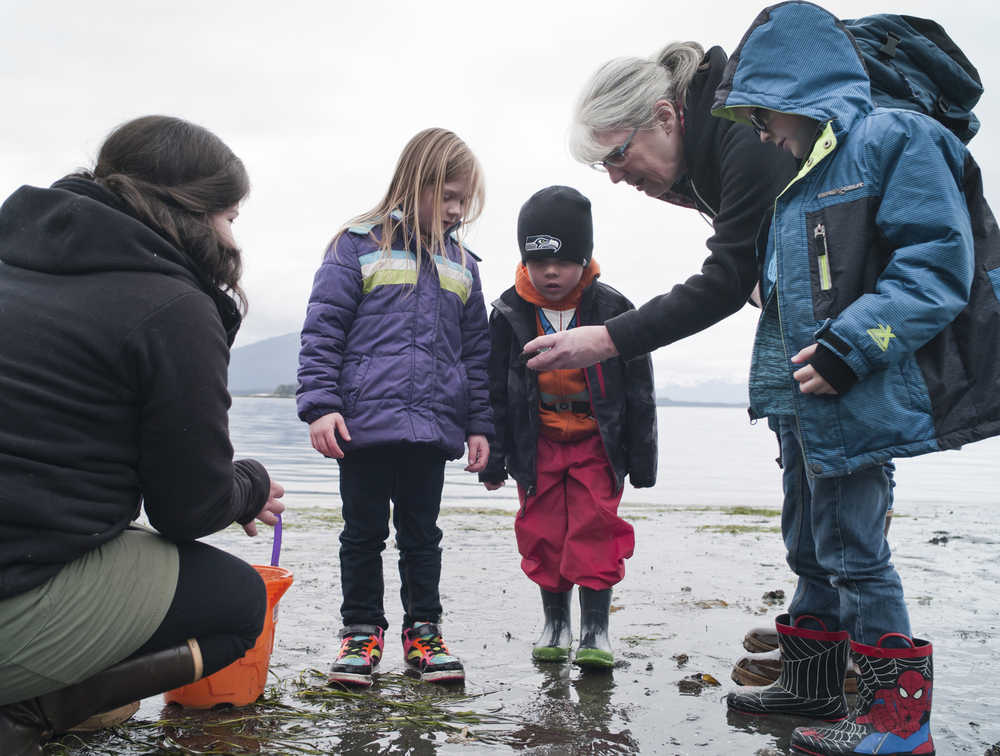Glacier Valley Elementary School kindergarten teacher Joann Steininger, right, and parent Kayla Tripp help students Aubrey Ridle, left, Alexander Tripp, center, and Parker Henderson learn about what lives in the intertidal zone during Monday's low tide at Auke Recreation Beach.