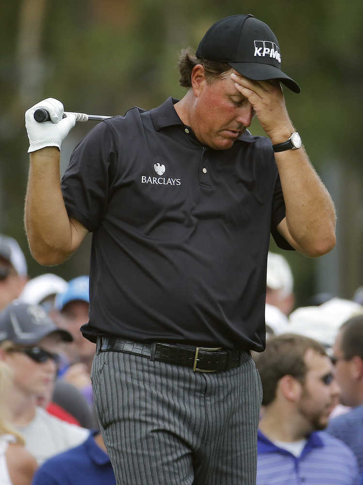 FILE - In this June 12, 2014, file photo, Phil Mickelson, right, reacts to his tee shot on the eighth hole during the first round of the U.S. Open golf tournament in Pinehurst, N.C. The Securities And Exchange Commission is filing a complaint against Mickelson related to insider trading. The SEC says, in 2012 high-profile sports bettor Billy Walters called Mickelson, who owed him money, and urged him to trade Dean Foods stock. The SEC says Mickelson did so the next day and made a profit of $931,000.  The SEC says Walters received tips and business information about Dean Foods Co. from former Dean Foods director Thomas Davis between 2008 and 2012. (AP Photo/Matt York, File)