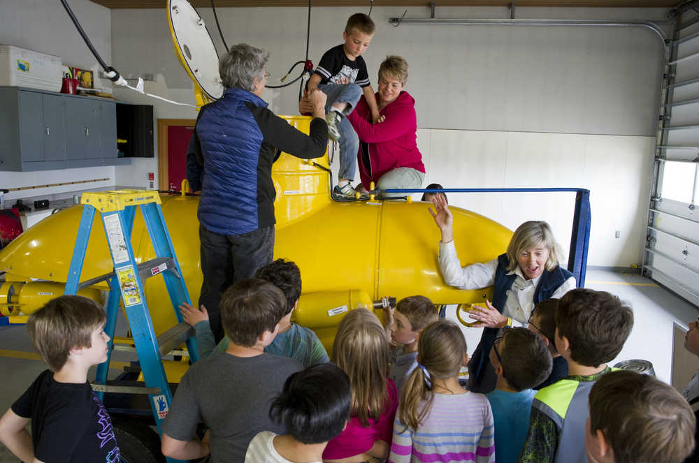 As first-grader Xander Webb is helped out of the top hatch, marine ecologist Michelle Ridgway, right, instructs other Faith Community Christian School students about the training submarine at the Auke Bay Fire Station on Tuesday.