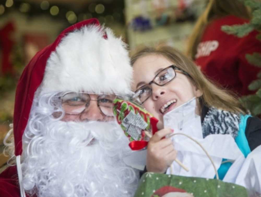 Caroline Robertson, 13, right, smiles and leans onto Santa Claus on Wednesday in the Christmas in Alaska store. Robertson has trisomy 18, also known as Edwards Syndrome, and asked the Make-A-Wish Foundation if she could meet Santa in Alaska.