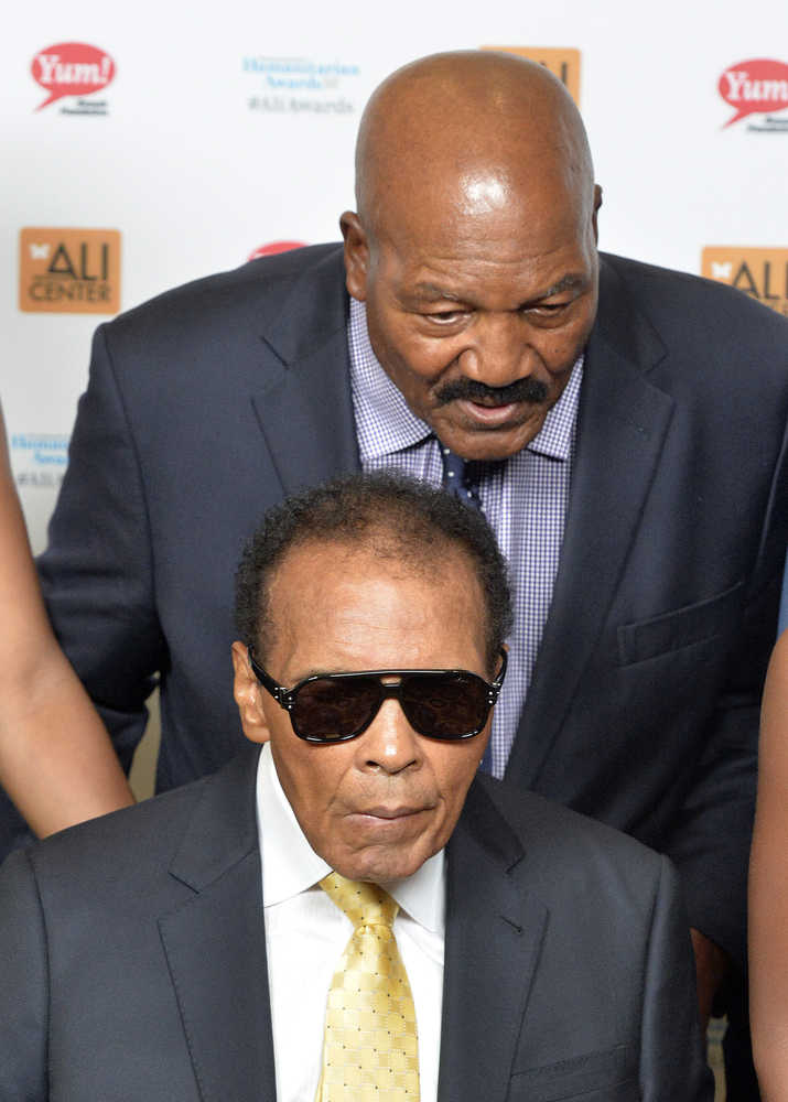 FILE - In this Sept. 27, 2014, file photo, Jim Brown, rear, whispers a message to Muhammad Ali during their meeting before the Ali Humanitarian Awards ceremony, in Louisville, Ky. The message that Brown whispered was "You're the greatest of all time," Brown later told a reporter. Ali, the magnificent heavyweight champion whose fast fists and irrepressible personality transcended sports and captivated the world, has died according to a statement released by his family Friday, June 3, 2016. He was 74.  (AP Photo/Timothy D. Easley, File)